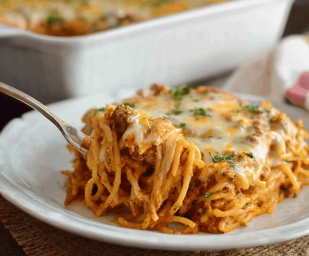 Creamy Southern Spaghetti Bake topped with melted cheese and fresh herbs, served in a casserole dish, perfect for a comforting family dinner.