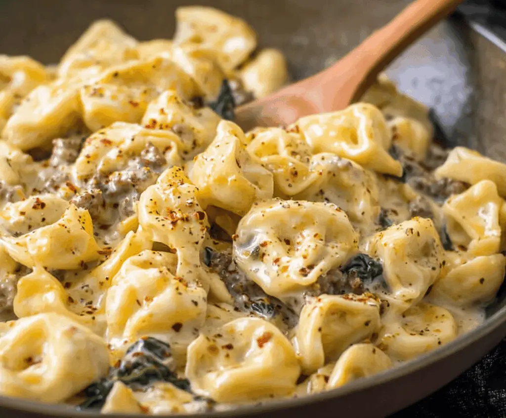 Delicious garlic butter beef and spinach tortellini served on a plate with fresh herbs, perfect for a flavorful Italian-inspired meal.