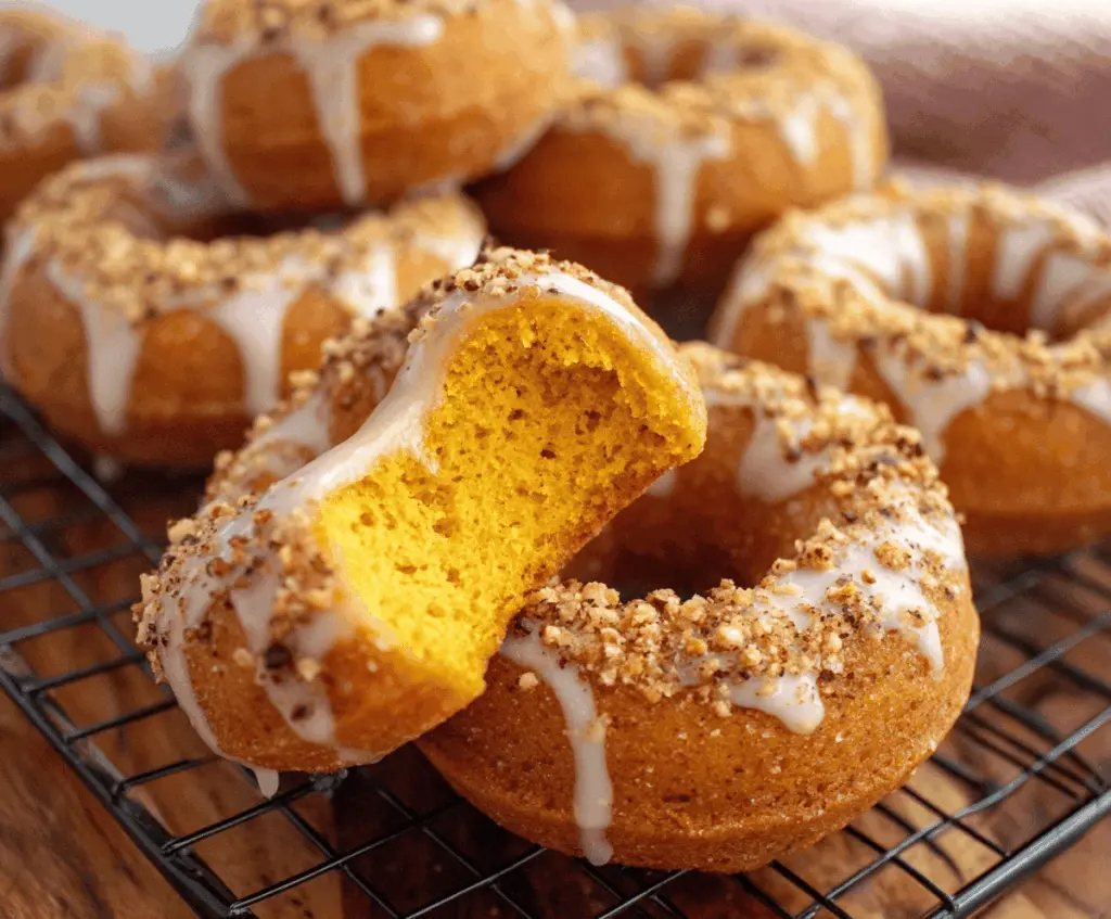 Delicious baked pumpkin cake donuts with cinnamon and nutmeg, topped with icing and sprinkles, on a rustic plate