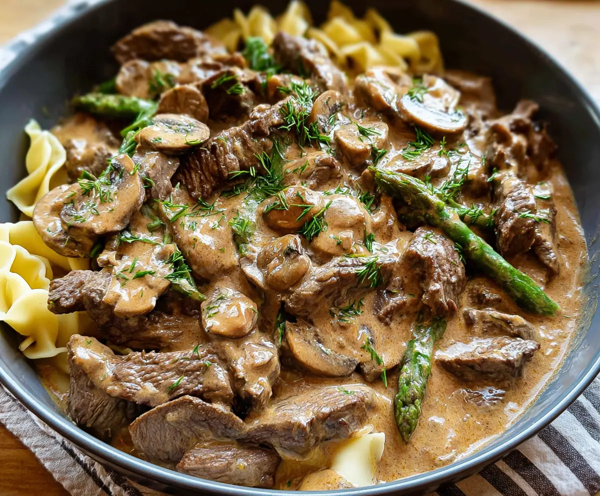 Creamy beef stroganoff served over noodles with fresh herbs.