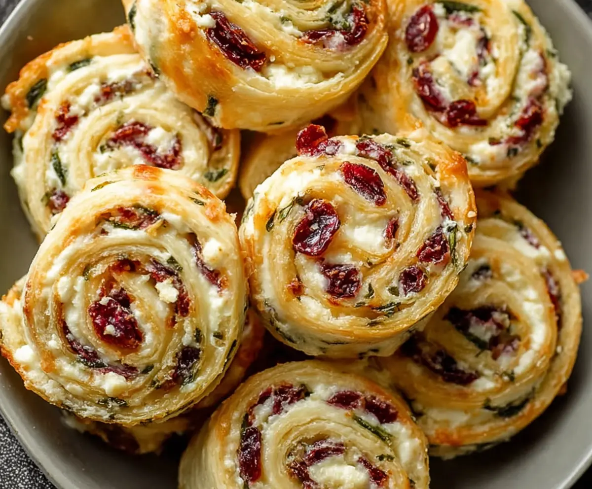 Delicious flaky cranberry cream cheese pinwheels on a white plate, perfect for parties