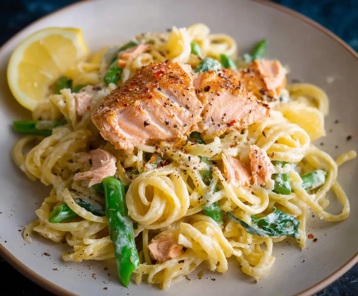 Delicious salmon pasta served with a creamy lemon sauce on a white plate.